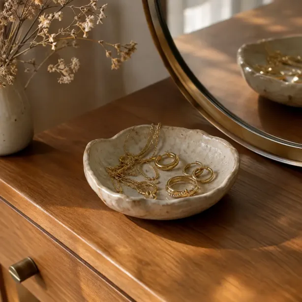 Biżuteria do warstw ułożona w ceramicznej miseczce na komodzie
